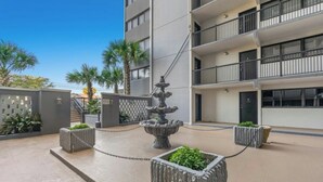Une cour avec une fontaine, des plantes en pot et un bâtiment moderne doté de balcons.