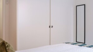 Ein Schlafzimmer mit einem Bett, einem Kleiderschrank und einem Spiegel an der Wand.