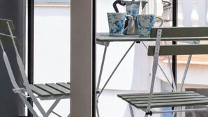 Ein Balkon mit Tisch und Stühlen, einem Fenster und einer Tür.