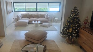En moderne stue med en hjørnesofa, et glasbord og et juletræ.