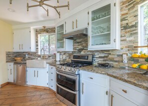A modern kitchen with granite countertops, stainless steel appliances, and a stone backsplash. - Iconic Lakeview Estate | 4BR | Sleeps 10 (Lake Arrowhead)