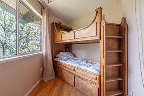 A bunk bed with a wooden headboard, a small bedside table, and a window with curtains. - Iconic Lakeview Estate | 4BR | Sleeps 10 (Lake Arrowhead)