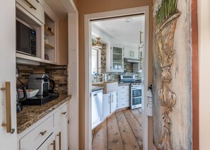 A kitchen with white cabinets, a granite countertop, and a wooden floor. - Iconic Lakeview Estate | 4BR | Sleeps 10 (Lake Arrowhead)
