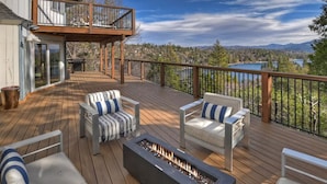 A deck with outdoor seating and a fire feature, overlooking a mountainous landscape. - Iconic Lakeview Estate | 4BR | Sleeps 10 (Lake Arrowhead)
