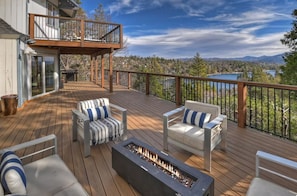A deck with outdoor seating and a fire feature, overlooking a mountainous landscape. - Iconic Lakeview Estate | 4BR | Sleeps 10 (Lake Arrowhead)