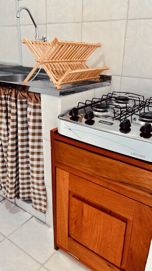 A kitchen with a gas stove, wooden drying rack, and checkered curtains. - Charming Apartment in the Heart of Belém, Amazon (Belém)