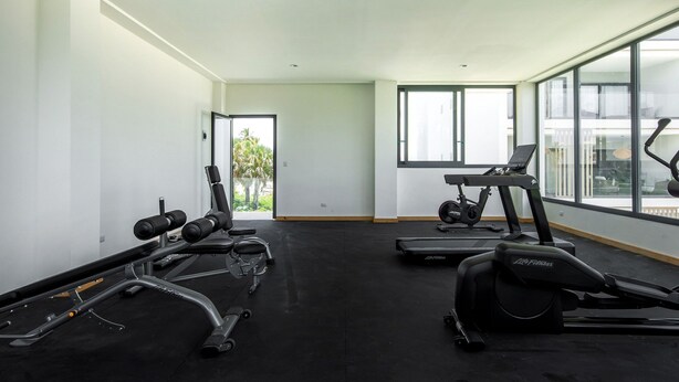Ett gym med konditionsmaskiner, styrketräningsutrustning och stora fönster.