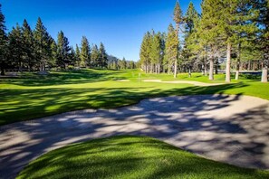 A golf course with a sand bunker, trees, and a clear sky. - Cozy Mammoth Condo | Hot Tub & Mountain Adventure (Mammoth Lakes)
