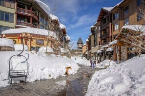 A snow-covered street with buildings, a ski lift, and a clear sky. - Cozy Mammoth Condo | Hot Tub & Mountain Adventure (Mammoth Lakes)