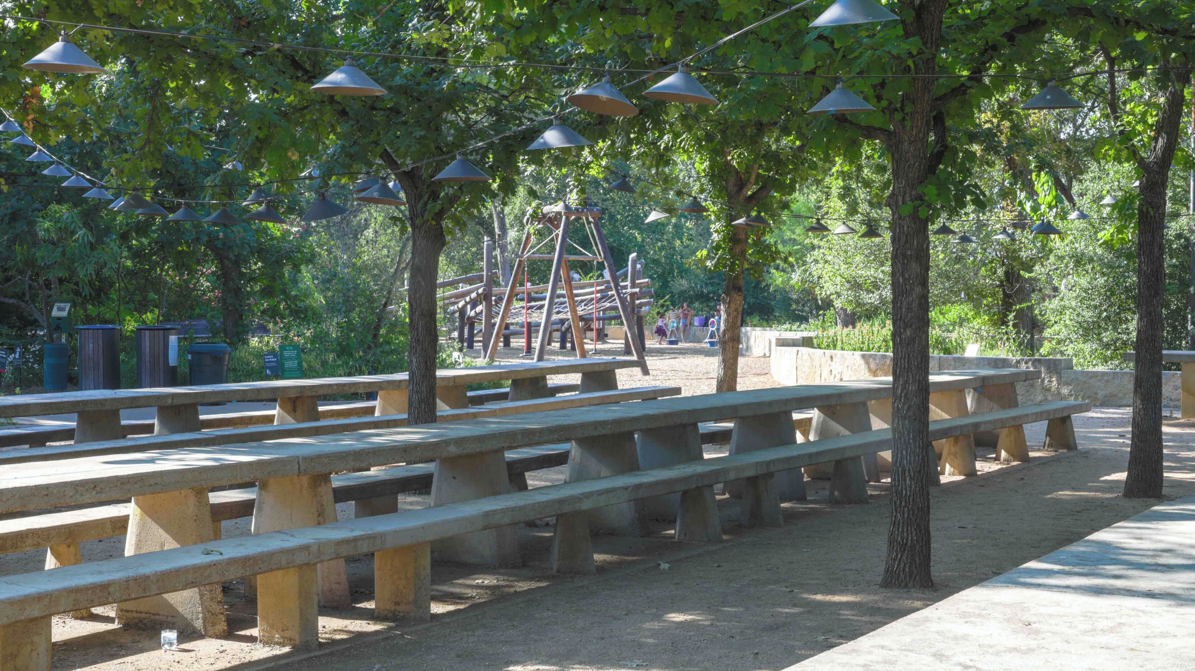 Outdoor picnic tables and swings in a park.