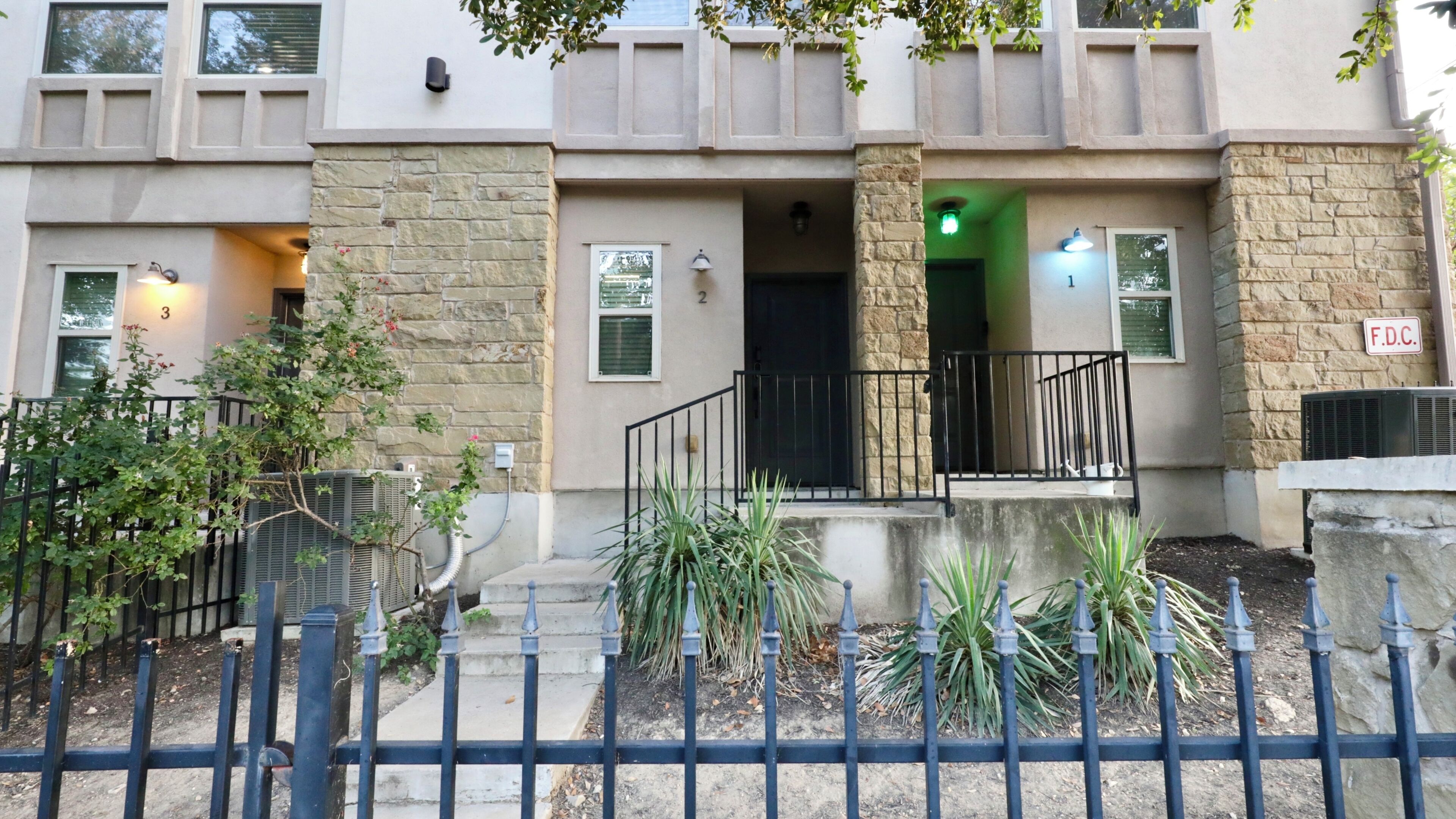 A multi-story residential building with a stone facade, numbered doors, and a gated entrance.