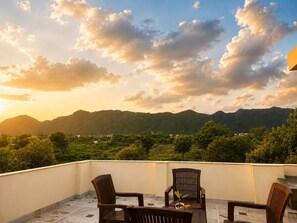 Eine Terrasse mit Tisch und Stühlen mit Blick auf eine gebirgige Landschaft.