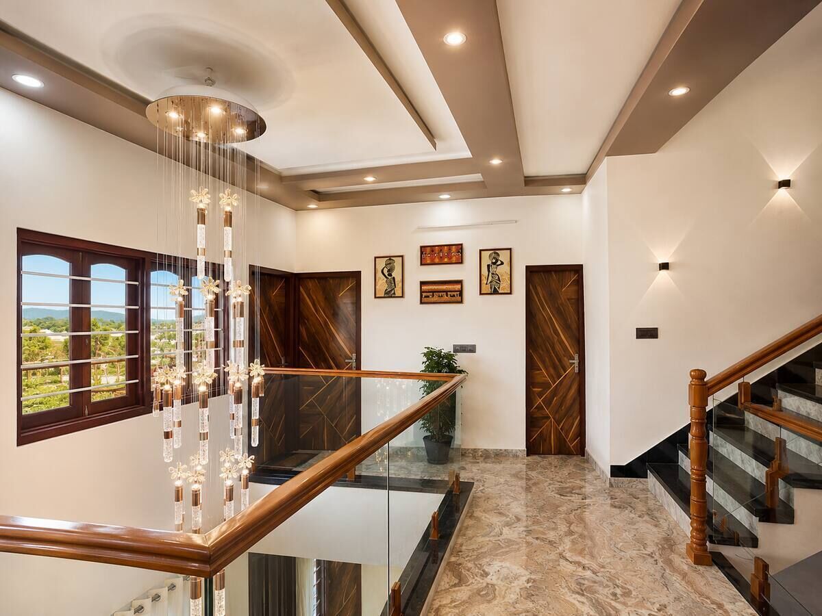 A modern interior with a glass railing, wooden staircase, and artwork on the walls.