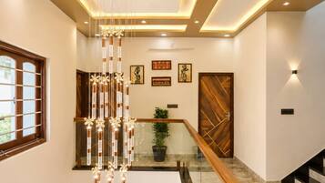 A modern interior with a staircase, a hanging light fixture, and a wooden door.