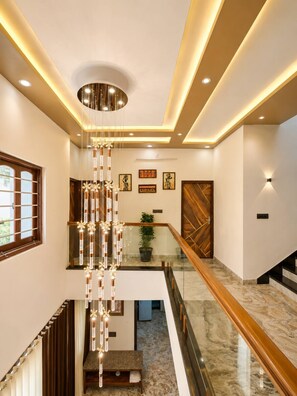 A modern interior with a staircase, a hanging light fixture, and a wooden door. - Luxury 4BHK Private Villa| Pool, Jacuzzi & Home Theater (Liyo Ka Gurha)