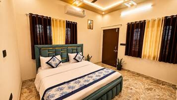 A bedroom with a bed, curtains, a ceiling fan, and an air conditioning unit.