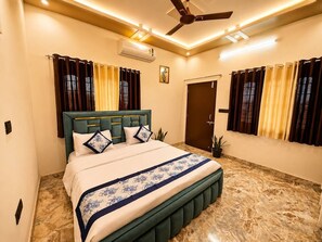 Ein Schlafzimmer mit Bett, Vorhängen, Deckenventilator und Klimaanlage.