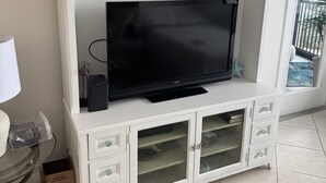 A white entertainment center with a flat-screen TV, decorative items, and a sign above reading 'NICK & LAURA.' - HAPPY PLACE! Charming condo in marvelous Siesta Key perfect for your getaway (Siesta Key)