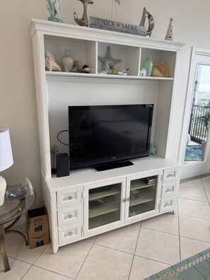 A white entertainment center with a flat-screen TV, decorative items, and a sign above reading 'NICK & LAURA.' - HAPPY PLACE! Charming condo in marvelous Siesta Key perfect for your getaway (Siesta Key)