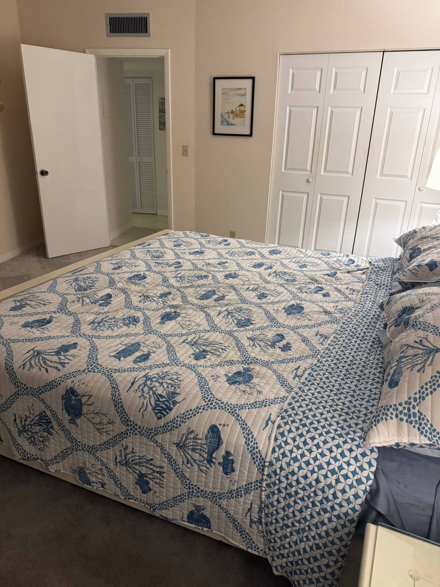 A bedroom with a bed, a door, a closet, and a framed picture on the wall.