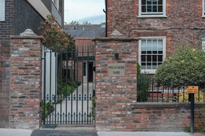 A brick building with a gate labeled 'PREACHERS YARD' and a sign indicating opening hours. - Preacher's Yard Stylish Central York Apartment - Courtyard 1 (York)