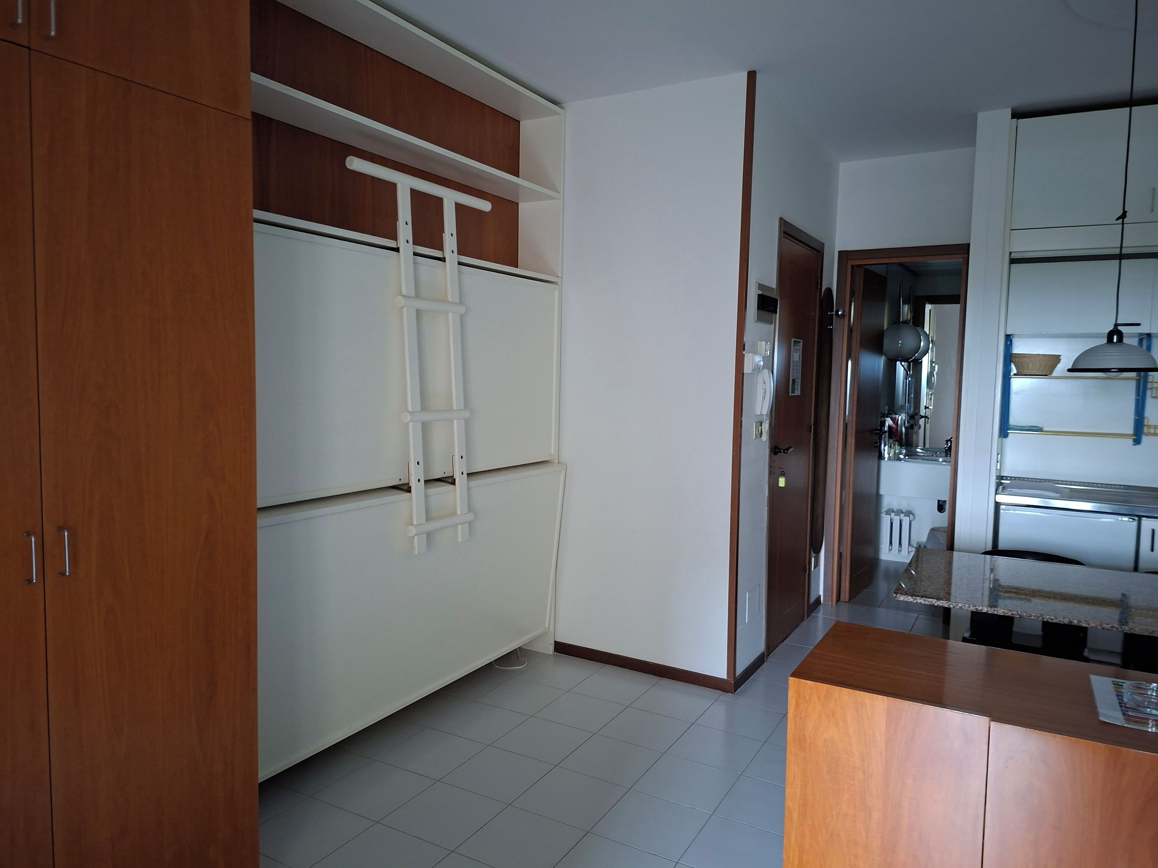 Una cocina con armarios blancos, encimera de madera y una escalera blanca.