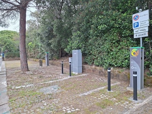 A parking area with electric vehicle charging stations, a no parking sign, and a payment kiosk.
