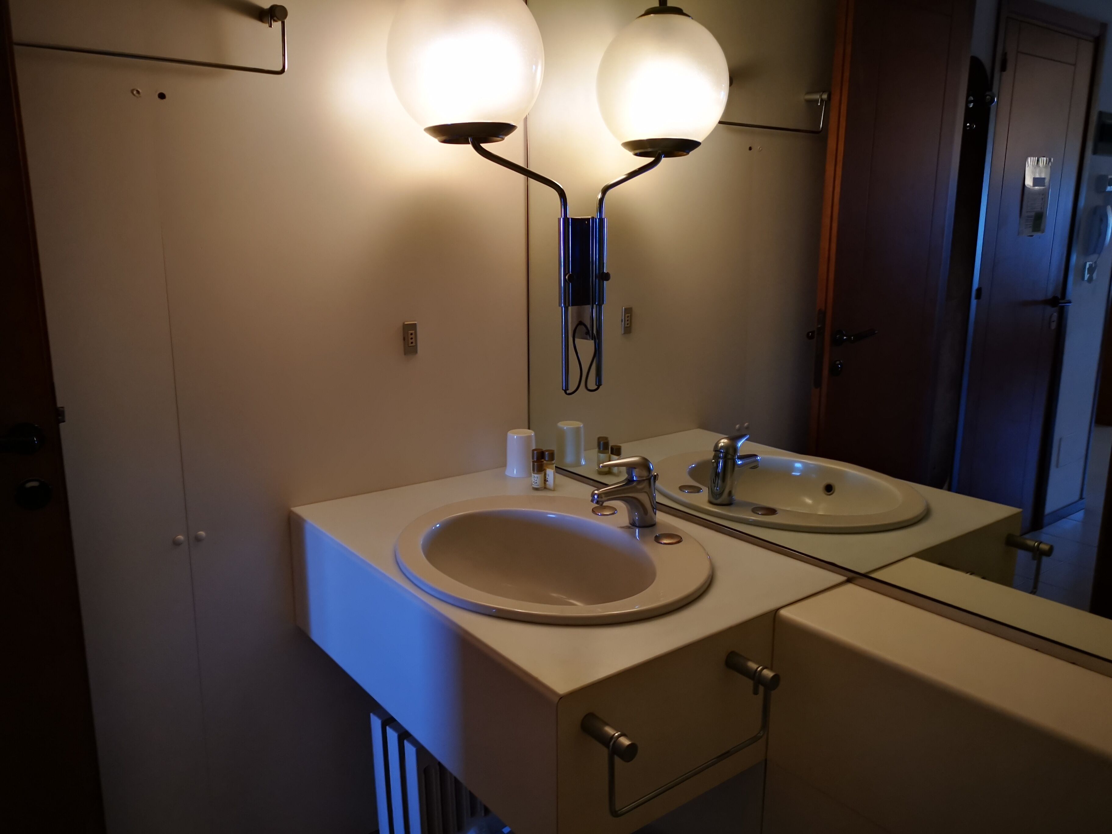 Ein Badezimmer mit einem Doppelwaschbecken, zwei Wandleuchten, einem Spiegel und einem Schrank.