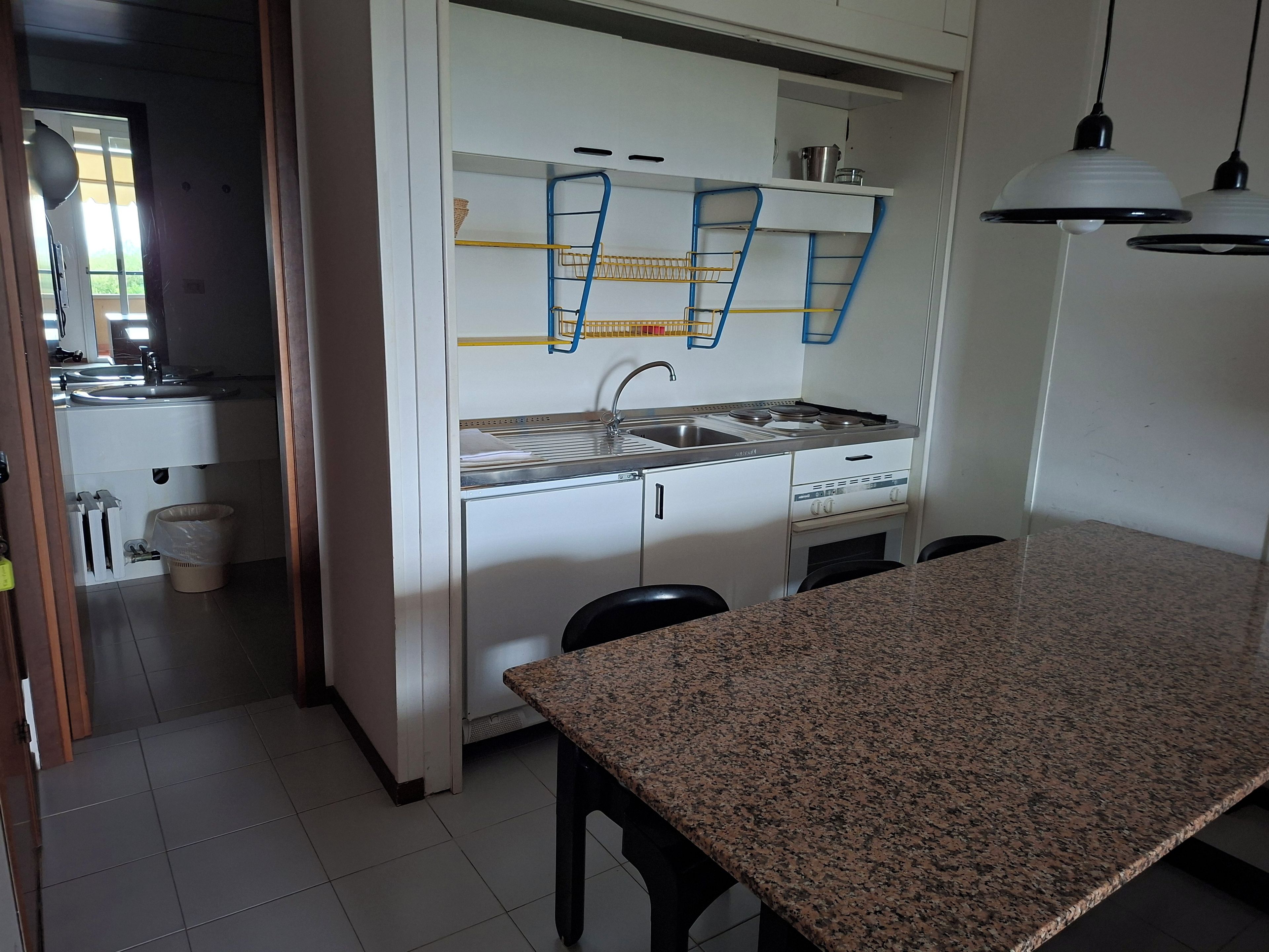 Una cucina compatta con un piano di lavoro in granito, un piano cottura integrato e un lavello.
