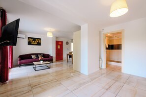 A modern living room with a sofa, coffee table, and a flat-screen TV. - Platinium 1 Apartment (Cannes)