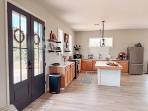 A modern kitchen with wooden cabinets, a central island, and a stainless steel refrigerator. - Modern Lakefront on Toledo Bend, 3BR • Sleeps 7 • Boat Launch & Amazing Views (Many)