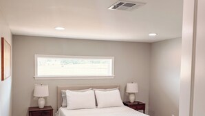 A bedroom with a bed, two bedside tables, a window, and a door. - Modern Lakefront on Toledo Bend, 3BR • Sleeps 7 • Boat Launch & Amazing Views (Many)