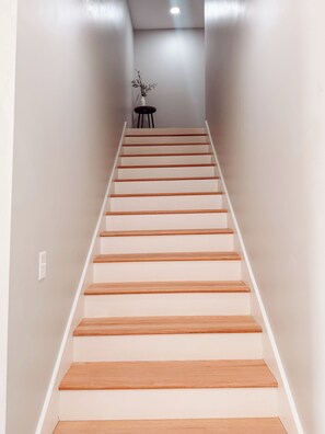 Eine Treppe mit Holzstufen und weißen Wänden, die zu einem Raum mit einem kleinen Tisch und einer Pflanze führt.