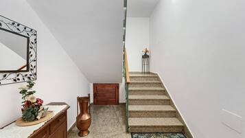A staircase with a wooden handrail, a small table with a vase of flowers, and a decorative mirror on the wall.