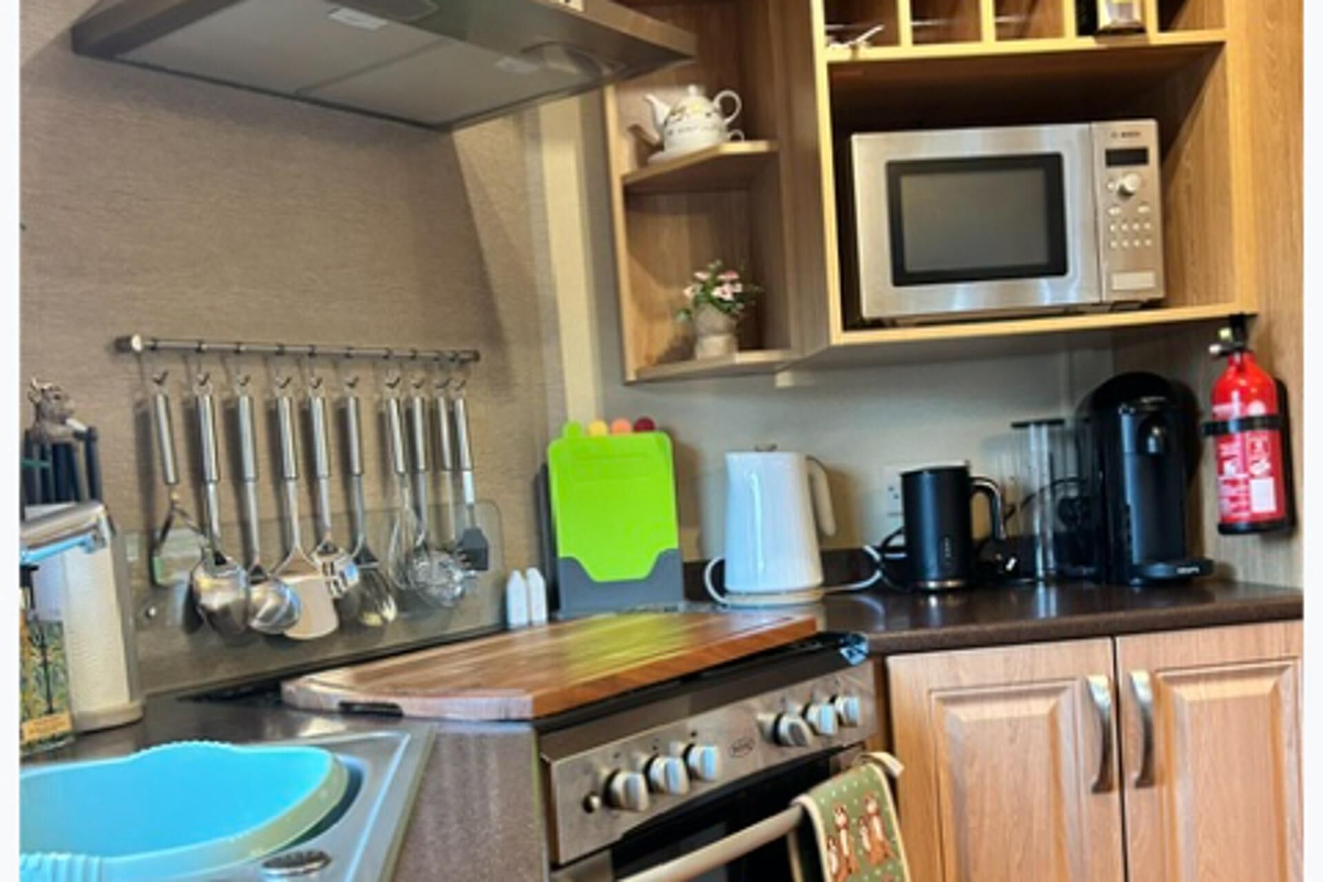 A kitchen with a stove, microwave, and various utensils.