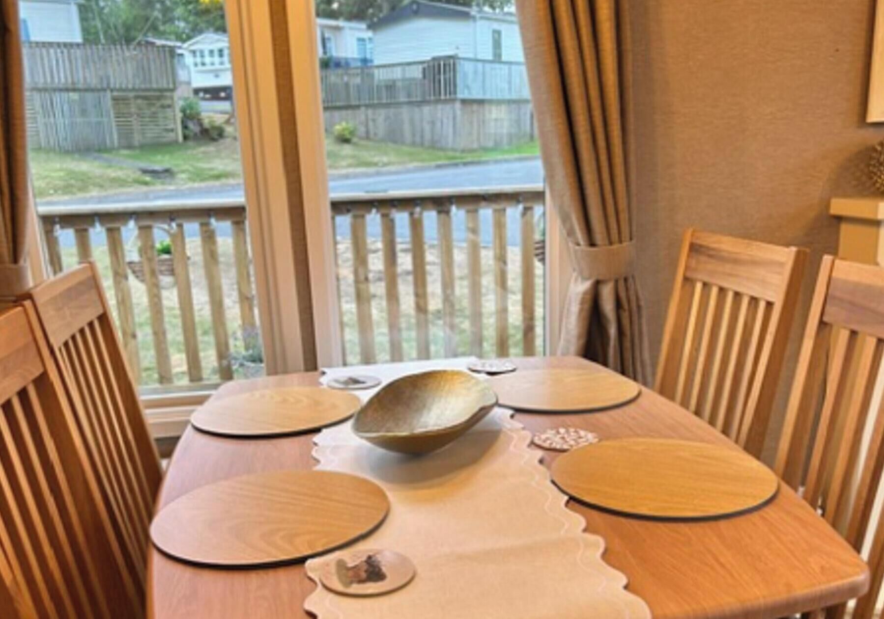 A dining table with wooden chairs, a placemat, and a bowl in the center.