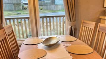 A dining table with wooden chairs, a placemat, and a bowl in the center.