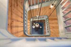 A wooden floor with a metal staircase railing and a hanging light fixture. - Casa do Ofício - Boilermaker 5 by Hosty (Porto)
