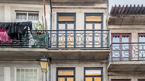 A multi-story building with a ground-floor shop, balconies with metal railings, and a fire hydrant on the sidewalk. - Casa do Ofício - Boilermaker 5 by Hosty (Porto)