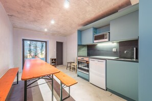 Eine kompakte Küche mit Mikrowelle, Backofen und Spüle. Es gibt eine Ablage und einen kleinen Tisch.