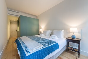 A hotel room with a bed, a nightstand with a lamp, a wardrobe, and a door leading to another room. - Casa do Ofício - Boilermaker 1 by Hosty (Porto)