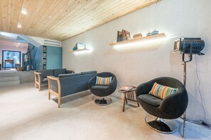A modern living room with a sofa, armchairs, a coffee table, and a bookshelf. - Casa do Ofício - Boilermaker 1 by Hosty (Porto)