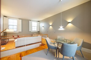 A modern bedroom with a bed, bedside tables, a glass table with chairs, and wall-mounted lights. - Casa do Ofício - Bookseller 3 by Hosty (Porto)