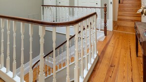 A staircase with white balusters and a wooden handrail leading to a landing. - Casa do Ofício - Bookseller 3 by Hosty (Porto)