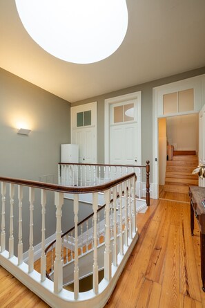 A staircase with white balusters and a wooden handrail leading to a landing. - Casa do Ofício - Bookseller 3 by Hosty (Porto)