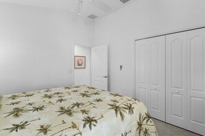 Een slaapkamer met een bed, witte muren, een deur en een kledingkast.