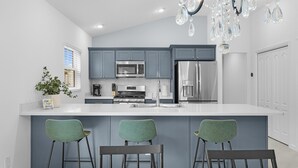 Una cocina moderna con armarios grises, electrodomésticos de acero inoxidable y una isla central con taburetes de bar.