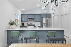 A modern kitchen with grey cabinets, stainless steel appliances, and a central island with bar stools. - Welcome to the Elegant 3/2 Courtyard Villa in the Village of Hawkins (The Villages)