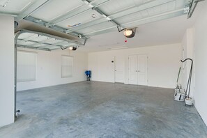 A spacious indoor area with a concrete floor, metal ceiling, and white walls. There are two doors, a window with blinds, and a blue folding chair. - Welcome to the Elegant 3/2 Courtyard Villa in the Village of Hawkins (The Villages)