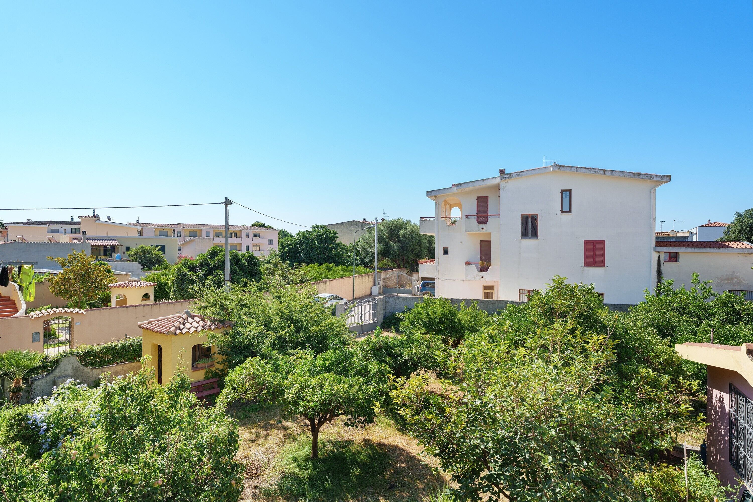 A residential area with a white building, trees, and a clear sky.